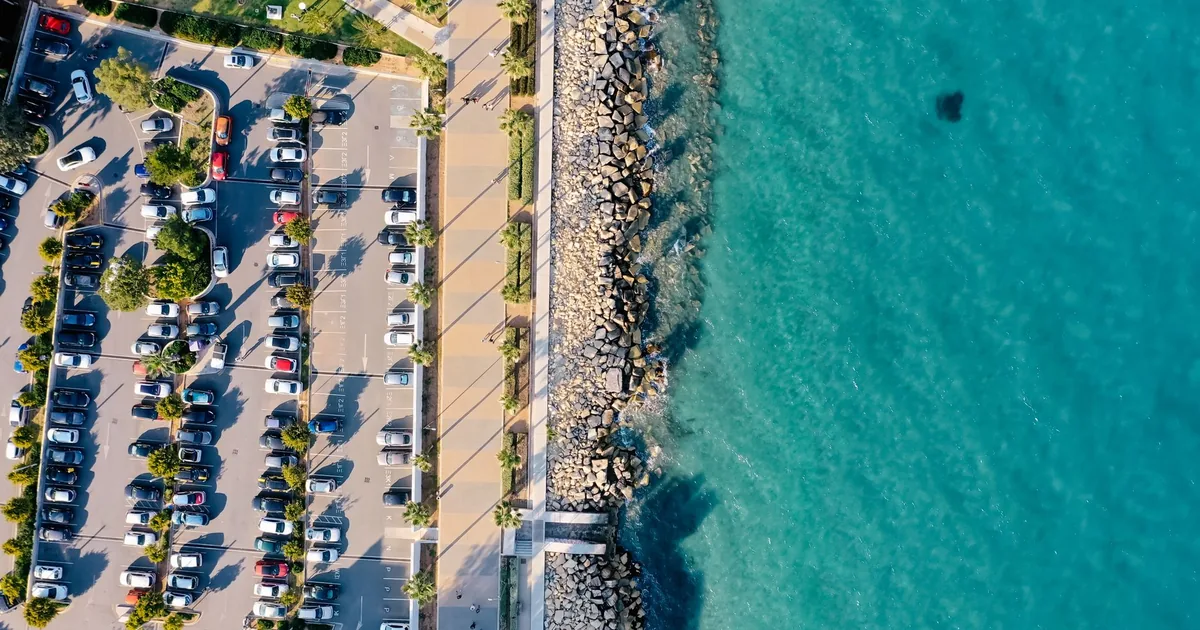 Aerial view of a busy parking lot next to a clear blue water.