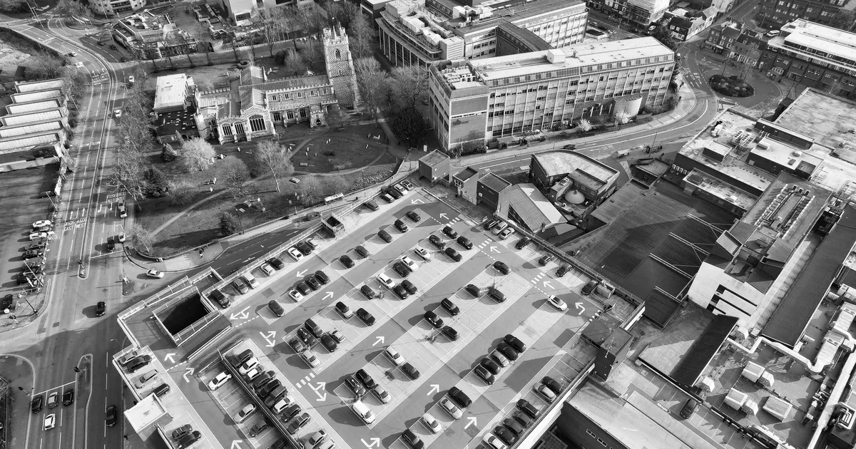 Aerial view of a busy parking lot with parked cars and surrounding.