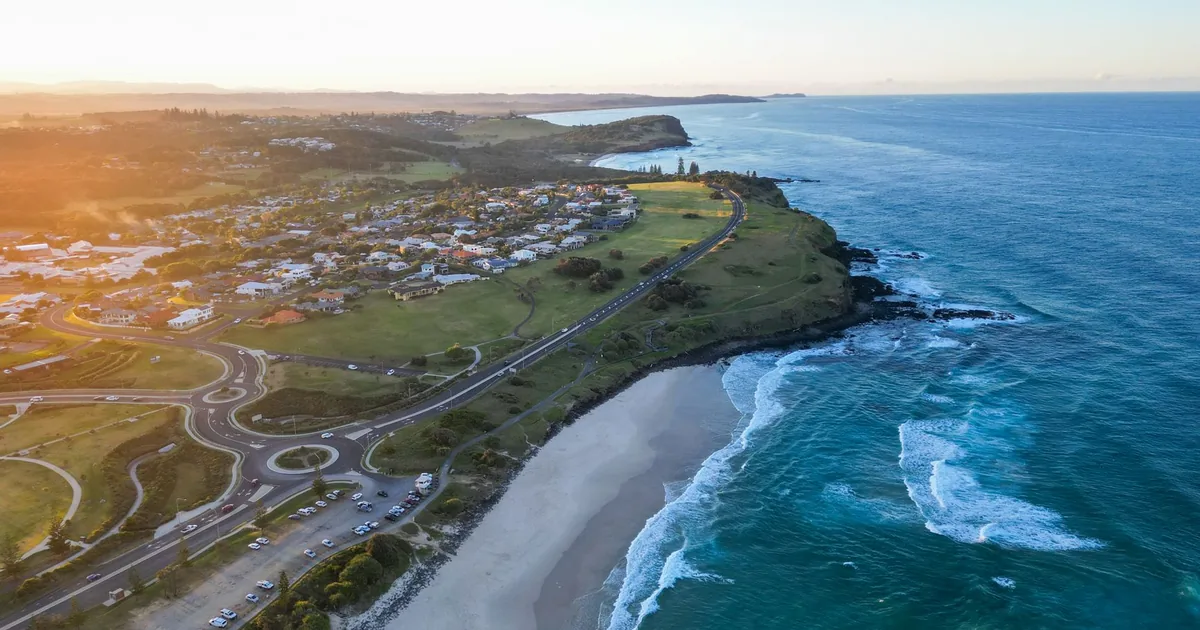 Aerial view of a coastal parking area beside the beach and ocean.