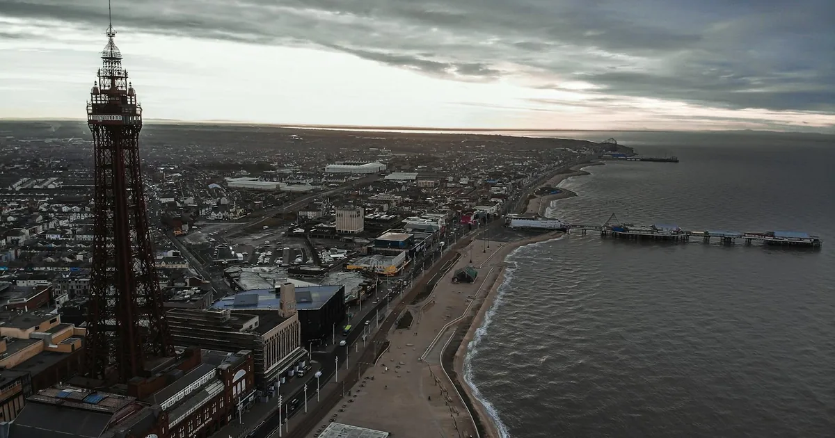 Aerial view of a coastal parking area near a beach and pier.