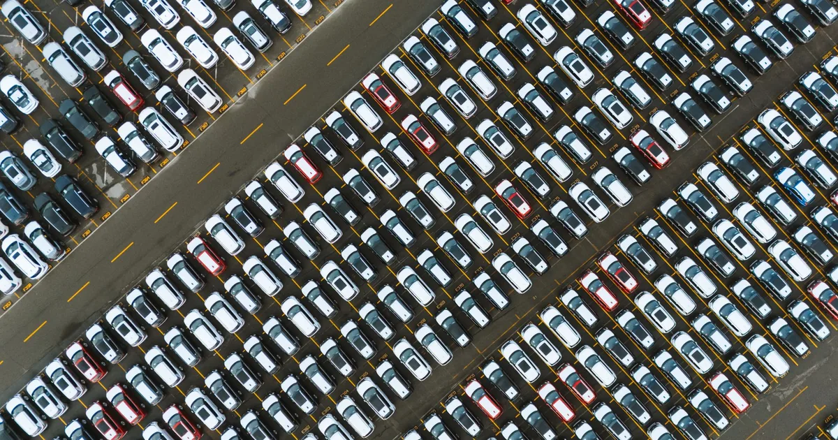Aerial view of a crowded parking lot filled with parked cars in rows.