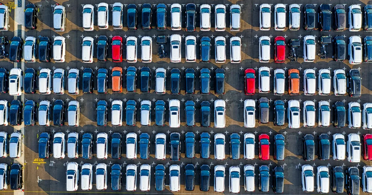 Aerial view of a crowded parking lot with rows of parked cars in.