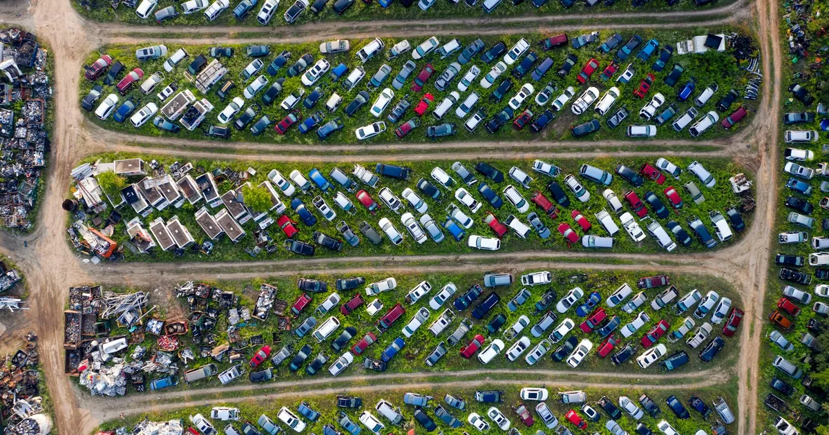 Aerial view of a large area filled with parked cars and greenery.