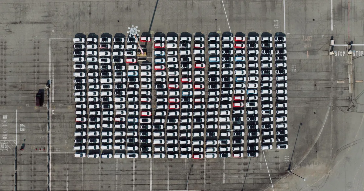 Aerial view of a large parking lot filled with rows of parked.