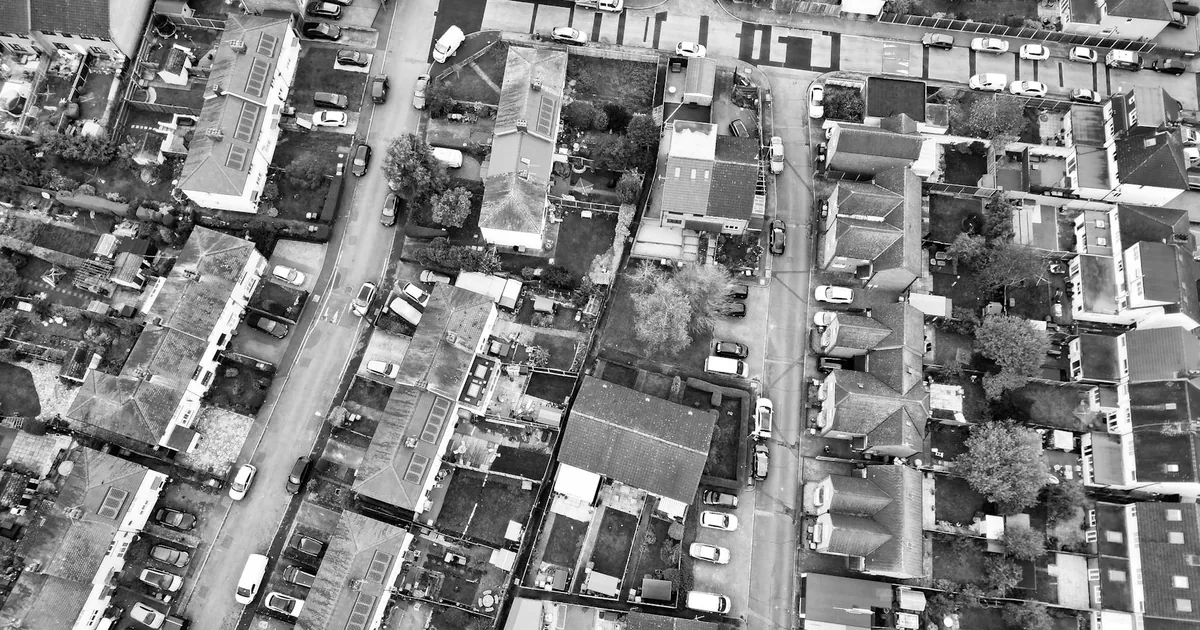 Aerial view of a neighborhood with parked cars along streets and.