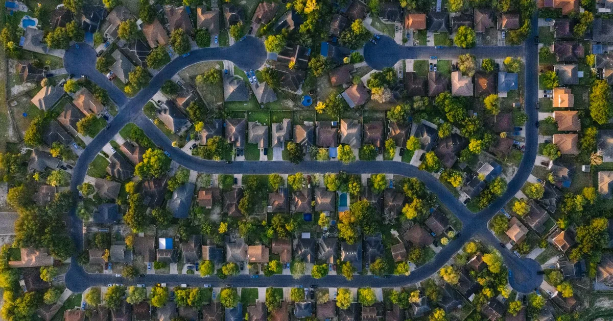 Aerial view of a neighborhood with parked cars along winding streets.