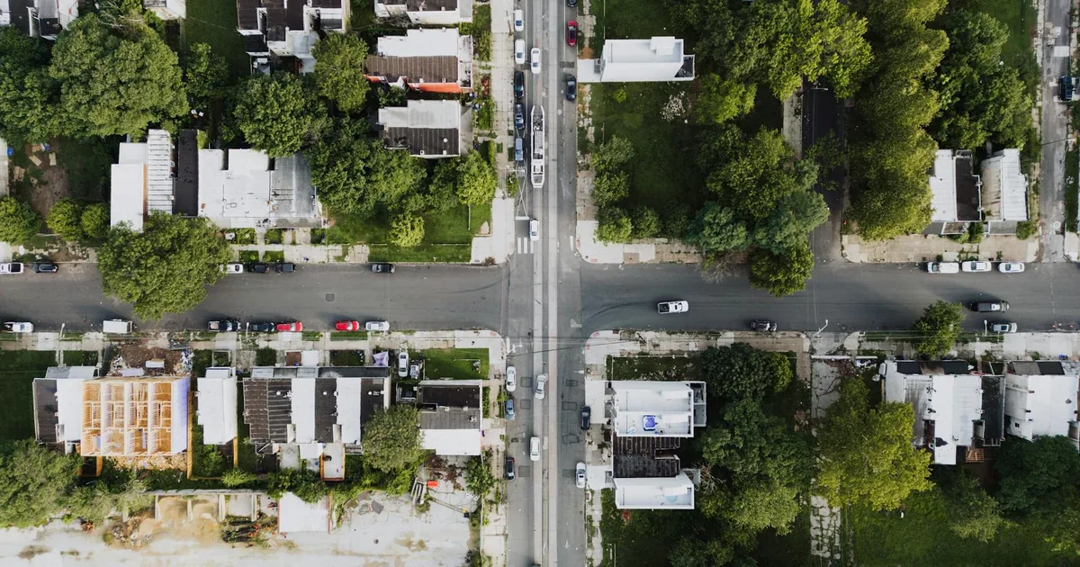 Aerial view of a neighborhood with parked cars and green trees.
