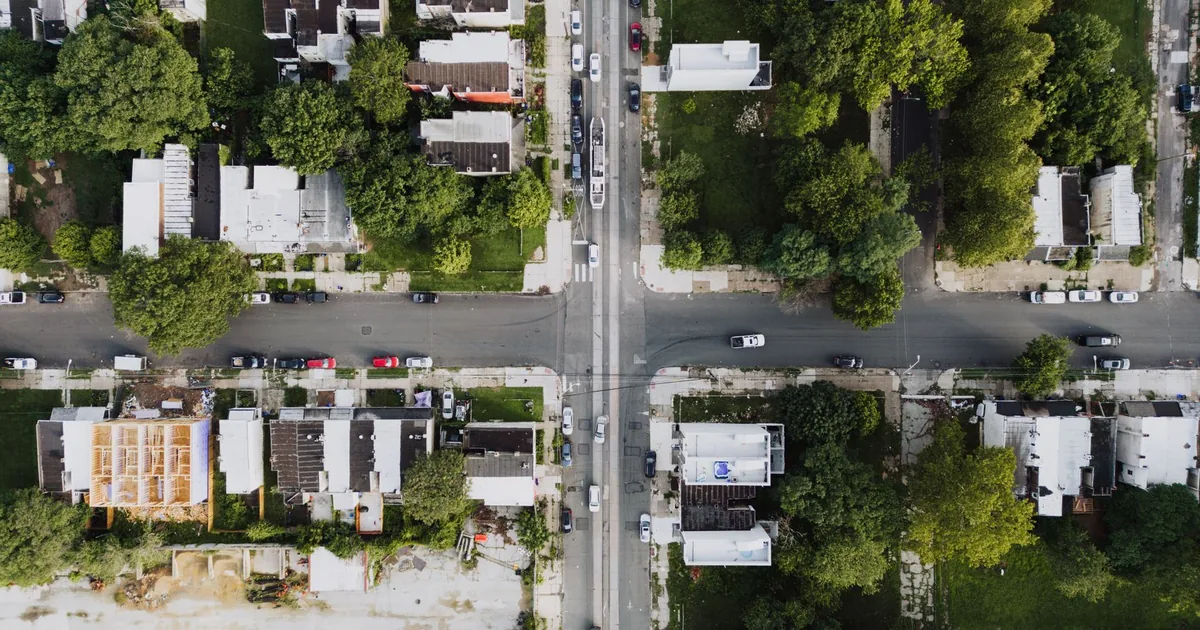 Aerial view of a neighborhood with parked cars and tree lined.