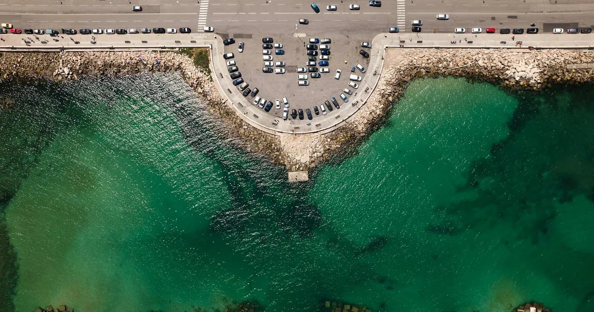 Aerial view of a parking area beside a body of water with vehicles.