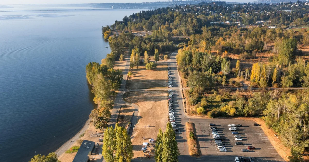 Aerial view of a parking area near a lake surrounded by trees and.
