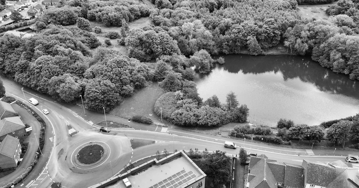 Aerial view of a parking area near a roundabout and a lake.