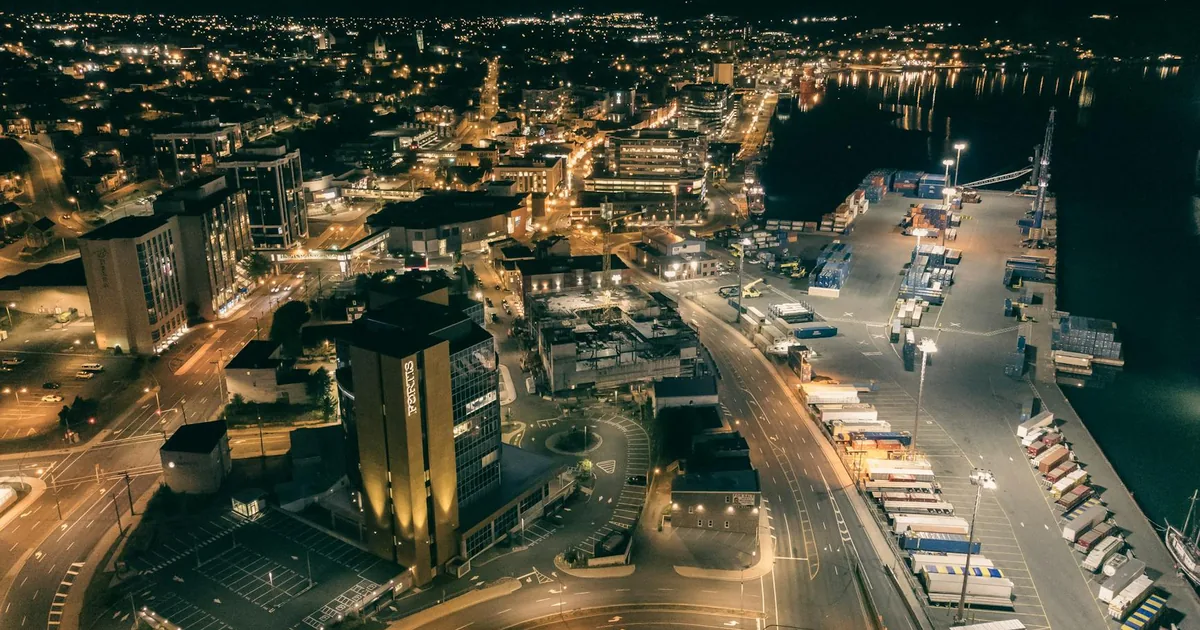 Aerial view of a parking area near a waterfront with city lights at.