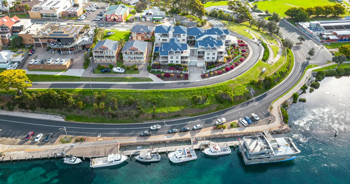 Aerial view of a parking area near waterfront with cars and boats.