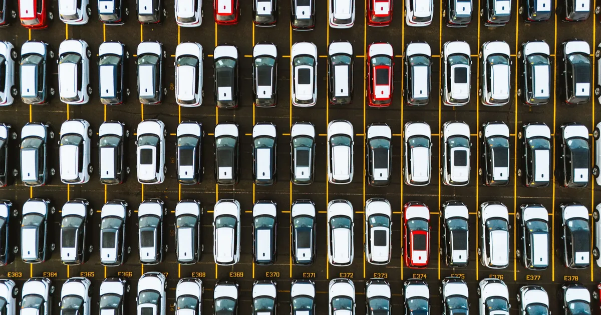 Aerial view of a parking lot filled with rows of parked cars in.
