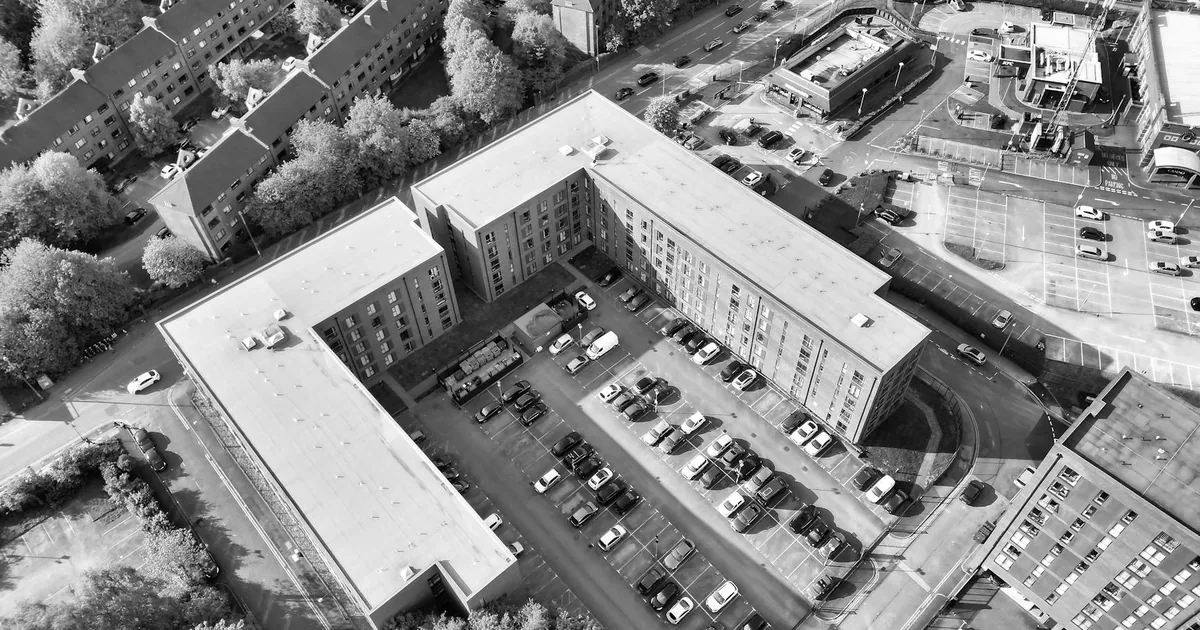 Aerial view of a parking lot surrounded by buildings and trees.