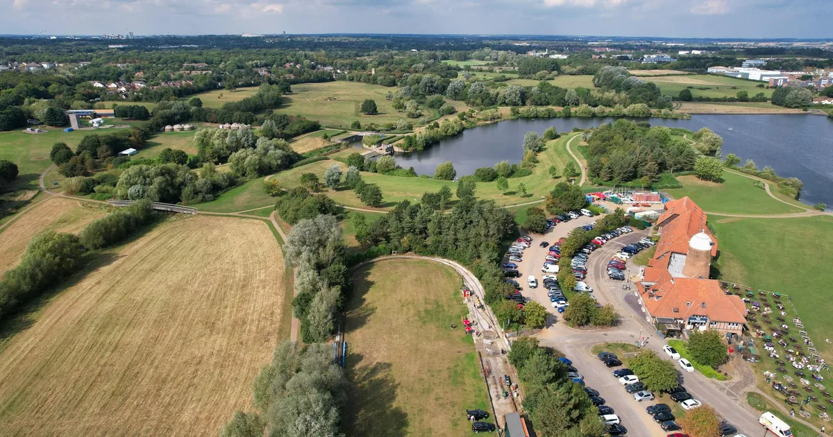 Aerial view of a parking lot surrounded by greenery and a lake.