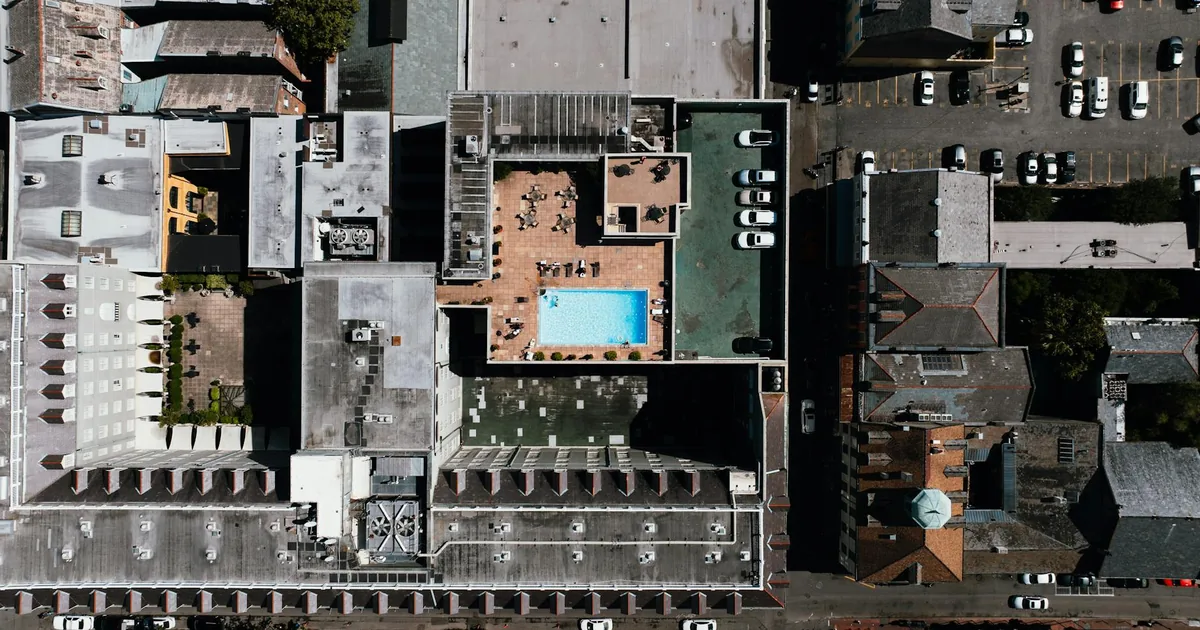 Aerial view of a parking lot with cars and a pool area visible.
