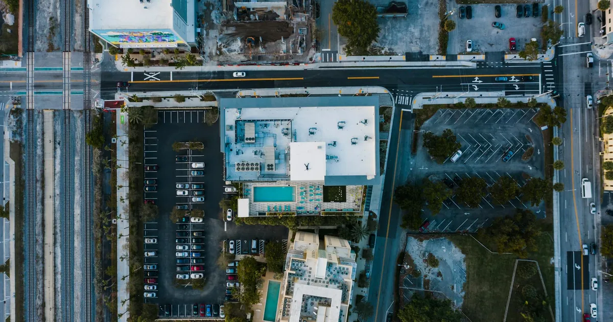 Aerial view of a parking lot with cars and nearby buildings and.