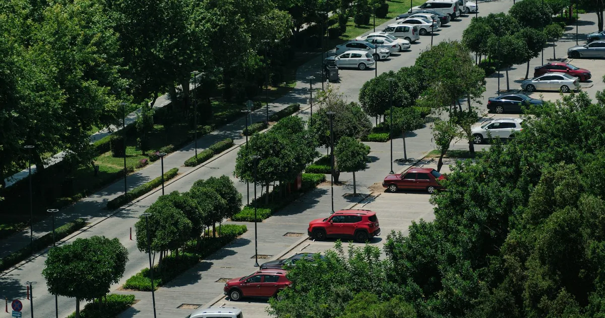 Aerial view of a parking lot with several cars and trees lining the.