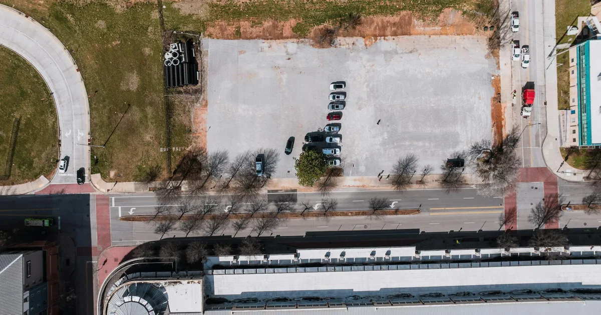Aerial view of a parking lot with several parked cars and.