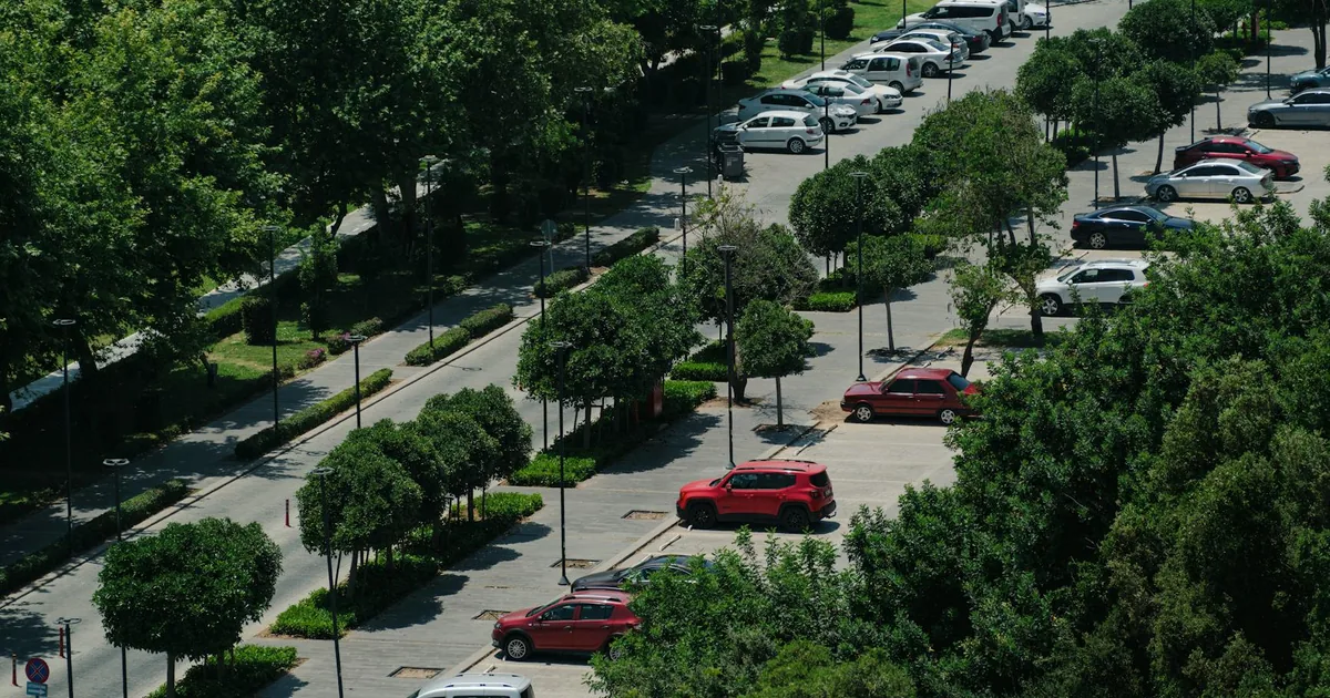 Aerial view of a parking lot with several parked cars and green.