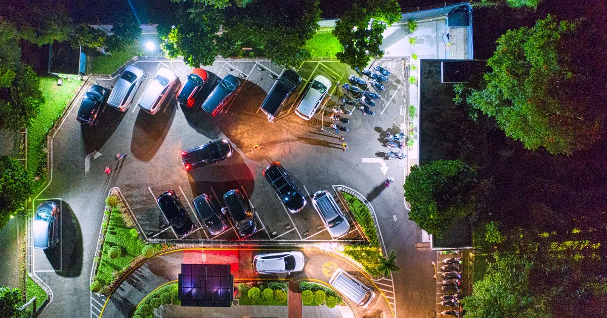 Aerial view of a parking lot with several parked vehicles and.