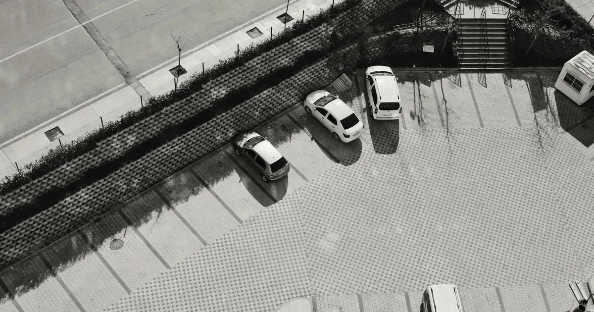 Aerial view of a parking lot with several parked vehicles and.