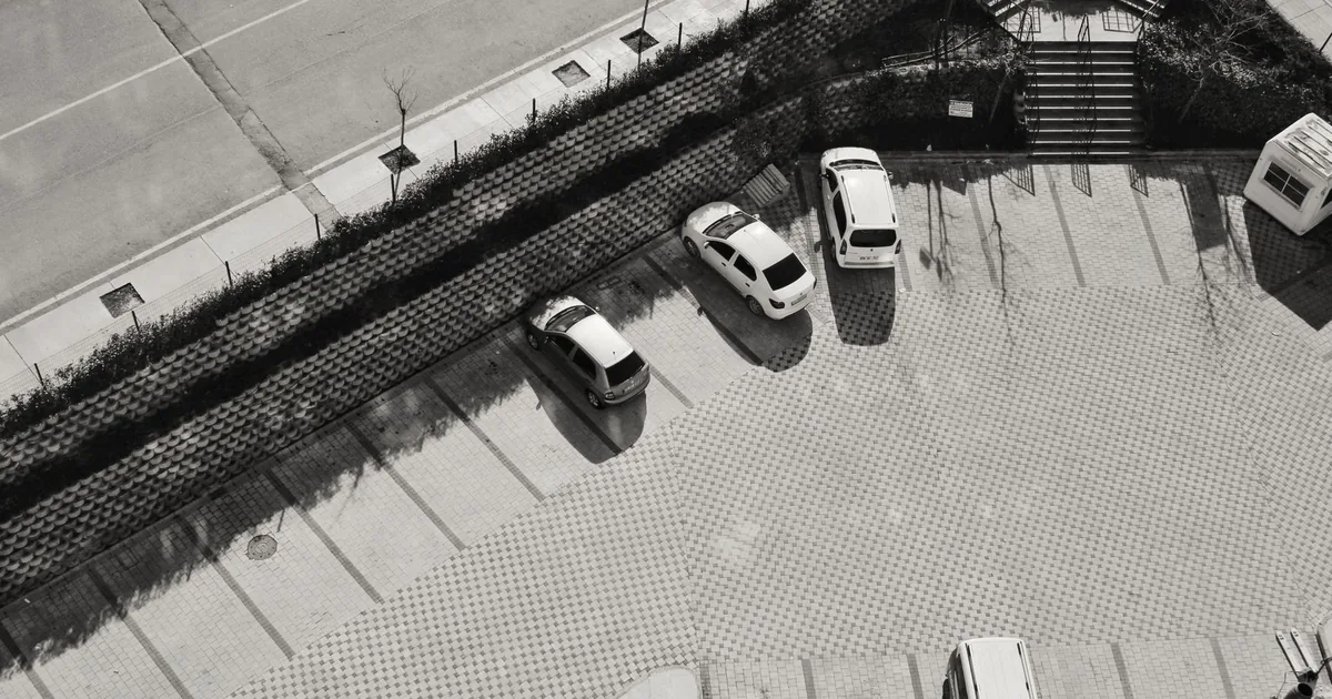 Aerial view of a parking lot with several parked vehicles and paved.
