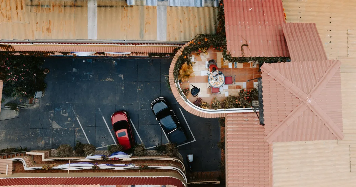 Aerial view of a parking lot with two cars and surrounding buildings.