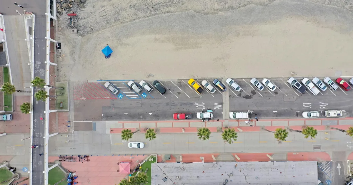 Aerial view of a parking lot with various parked cars near a beach.