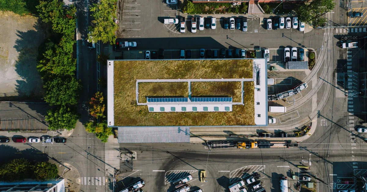 Aerial view of a parking lot with various vehicles and greenery.