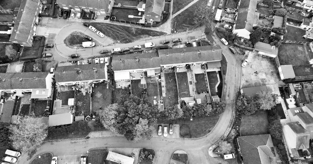 Aerial view of a residential area with parked cars and driveways.