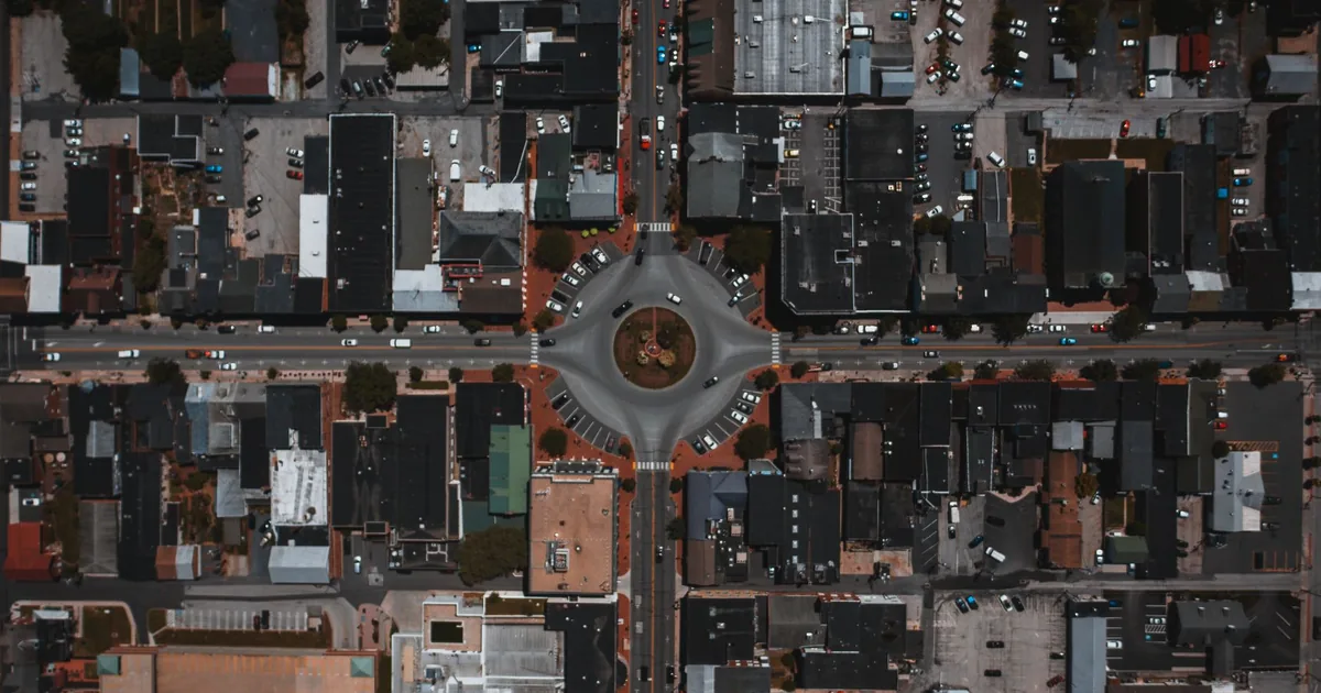 Aerial view of a roundabout surrounded by buildings and parked cars.