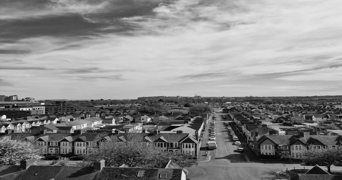 Aerial view of a street lined with parked cars and residential.