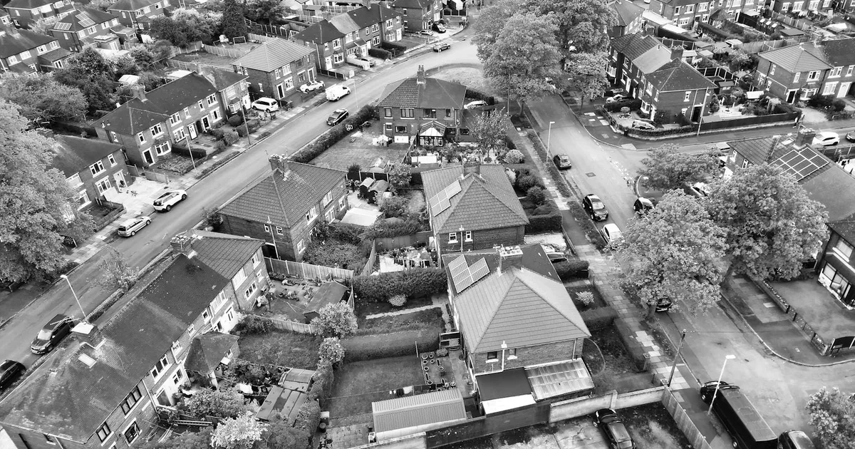 Aerial view of houses with parked cars on streets and driveways.