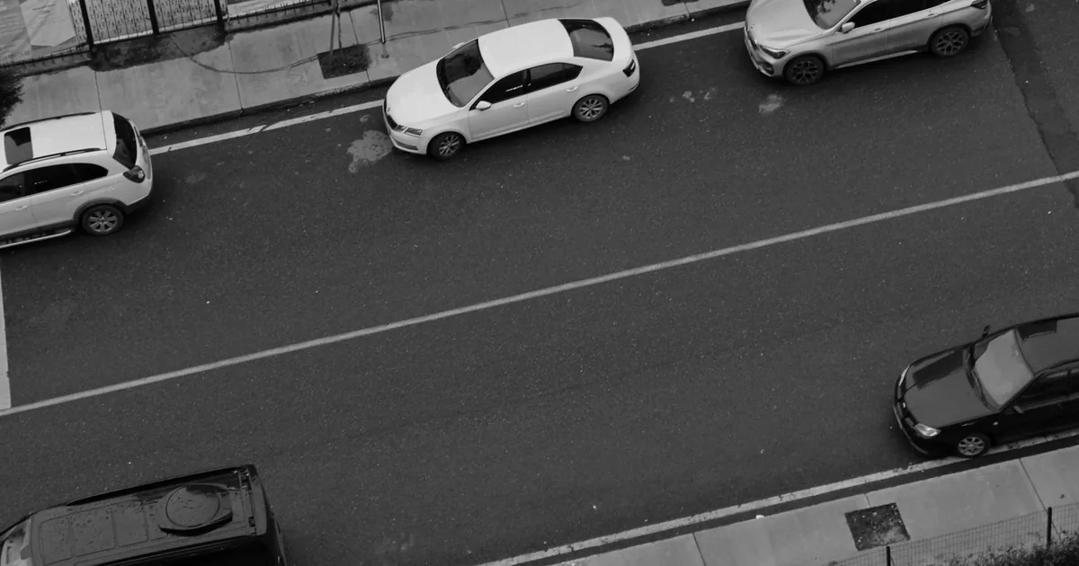 Aerial view of parked cars along a city street with clear road space.