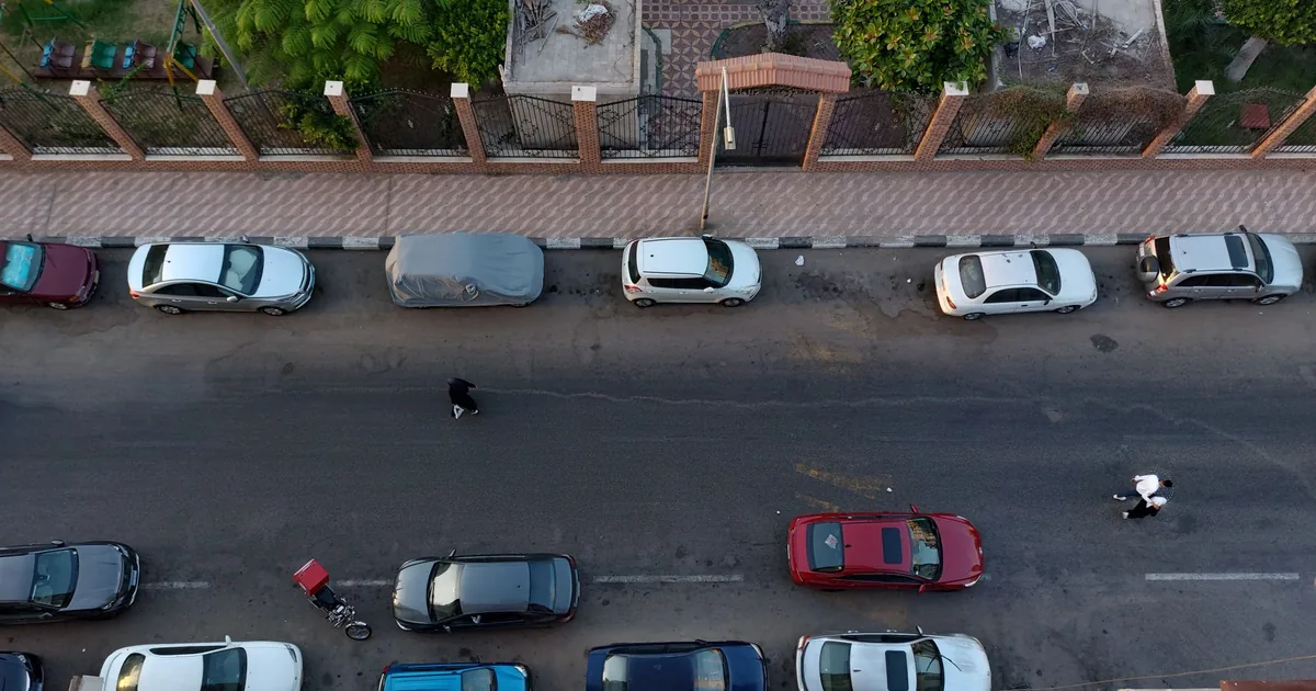 Aerial view of various parked cars along a street with a pedestrian.