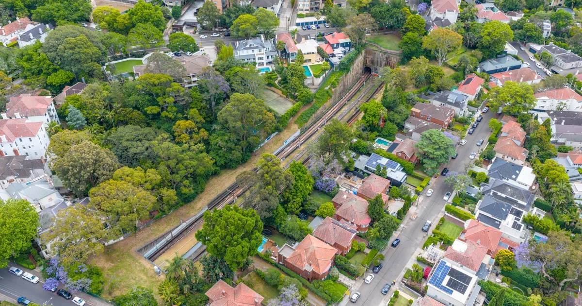 Aerial view showing homes trees and a parking area in a suburban.