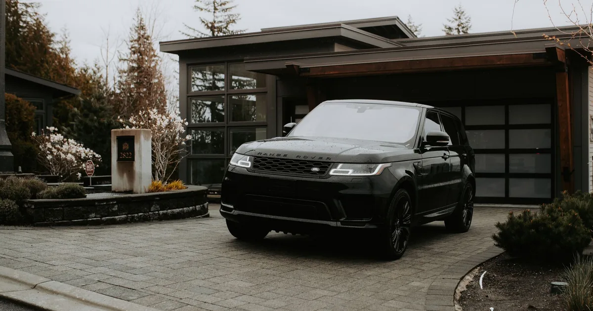 Black luxury vehicle parked in a modern residential driveway.