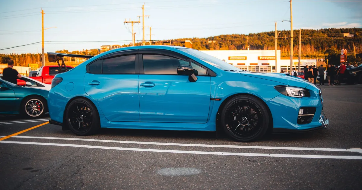 Blue car parked in a lot with clear lines and surrounding vehicles.