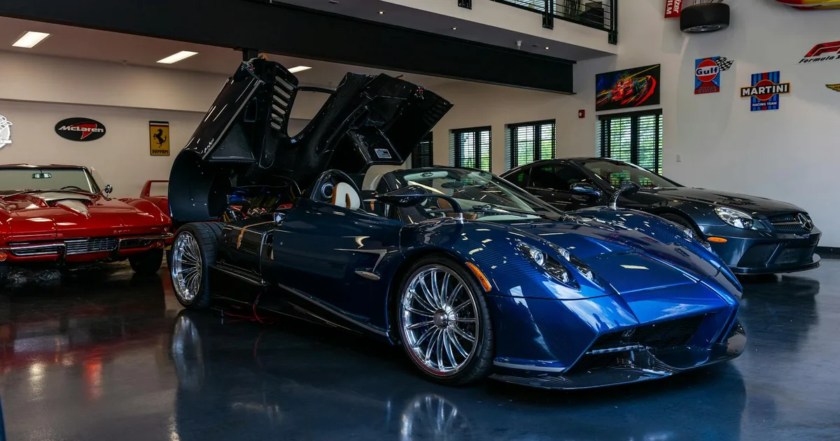 Blue luxury car with open doors parked in a well lit garage with.