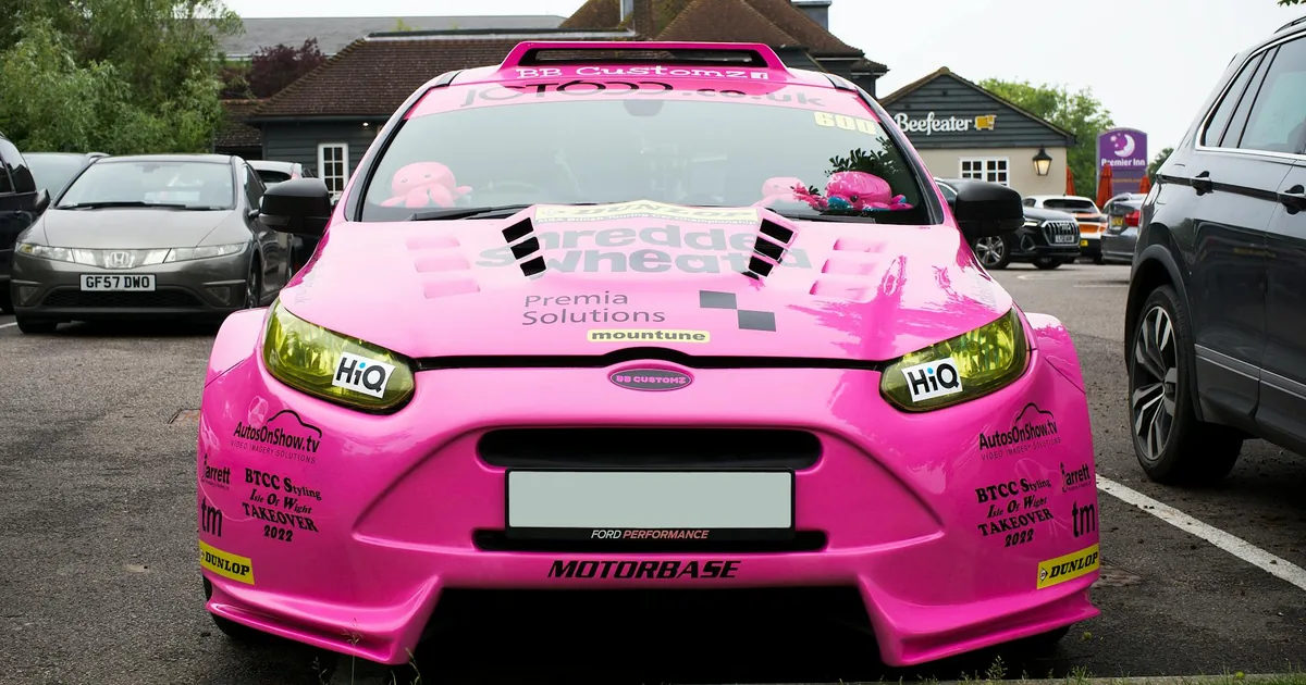 Bright pink car parked in a lot with other vehicles in the.