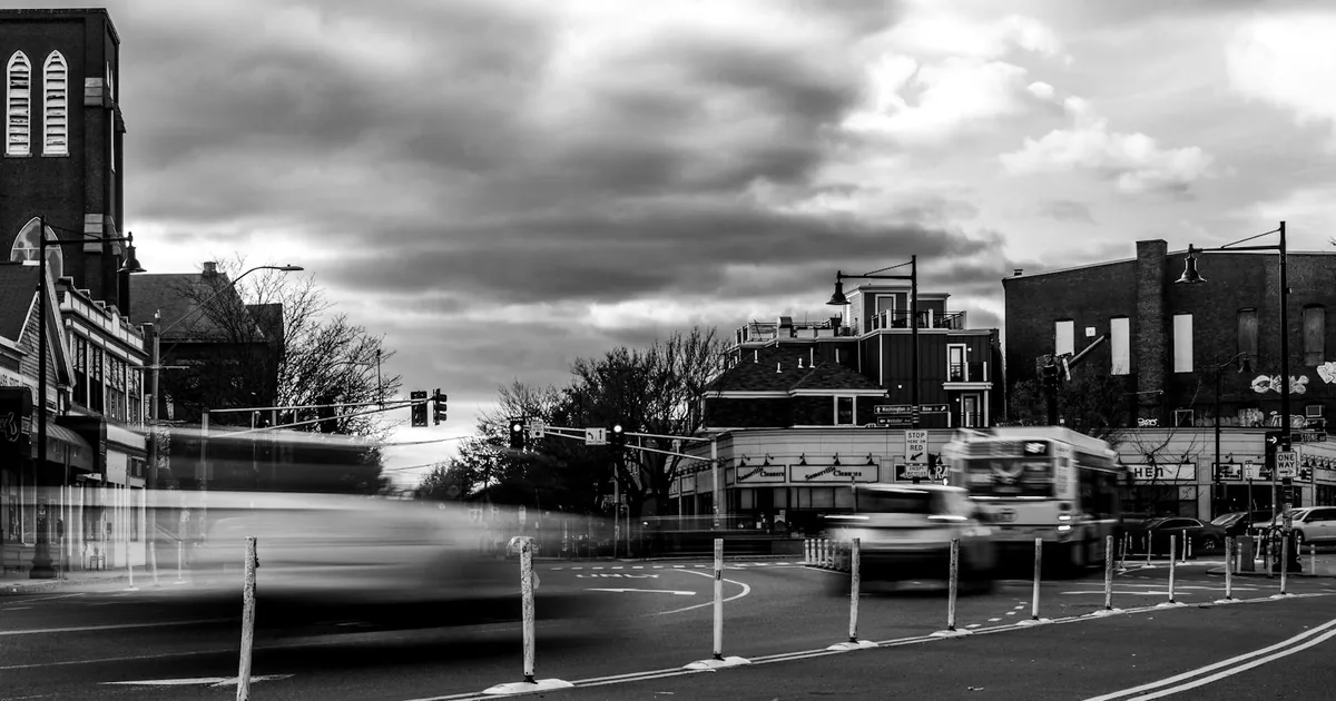 Bustling urban street with parked vehicles and traffic under a.