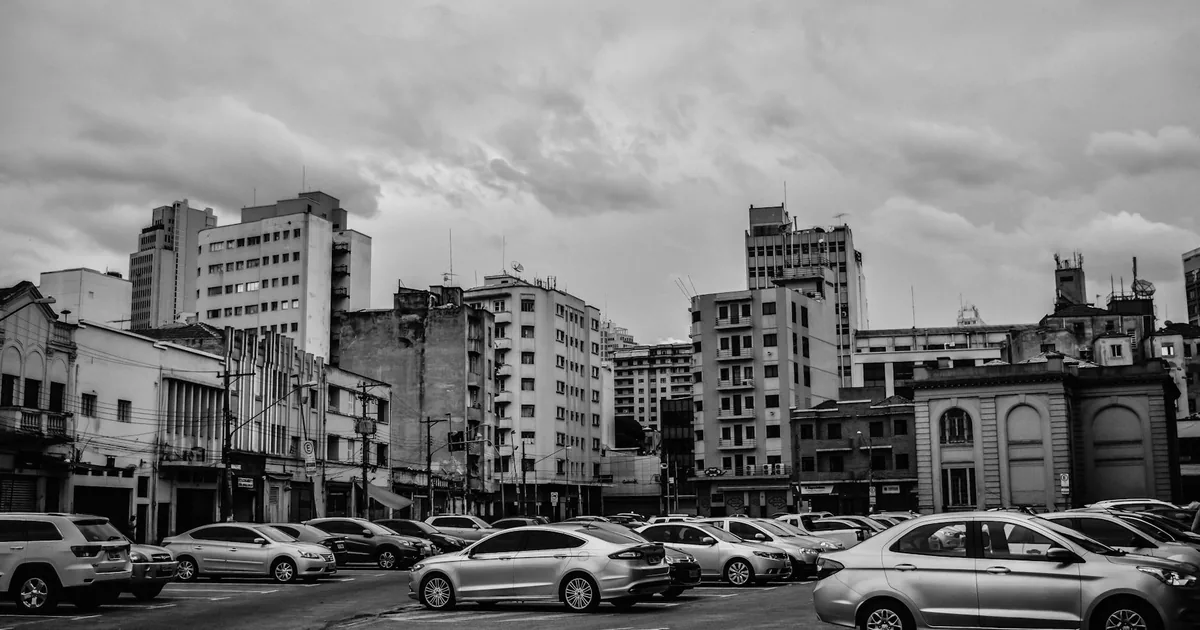 Busy urban parking lot filled with various parked cars and tall.