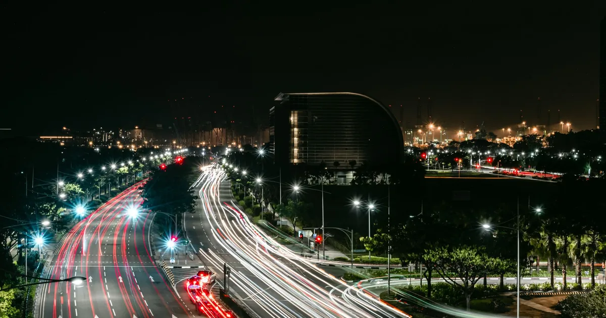 Busy urban road at night with parked cars and city lights in the.