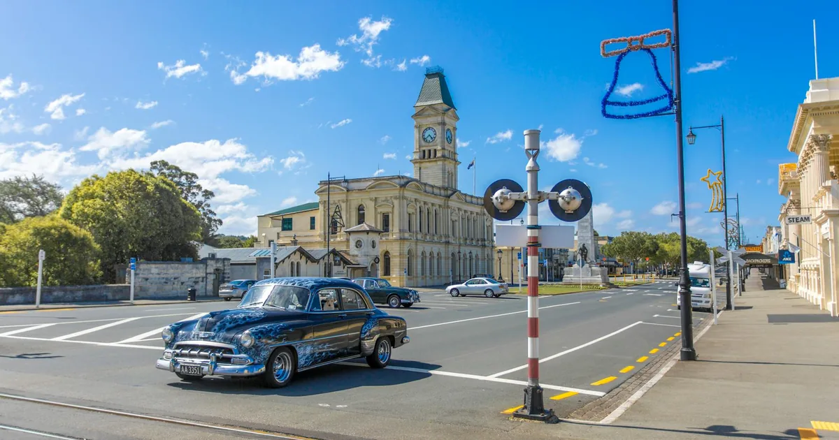 Classic car parked near a historic building on a sunny day.