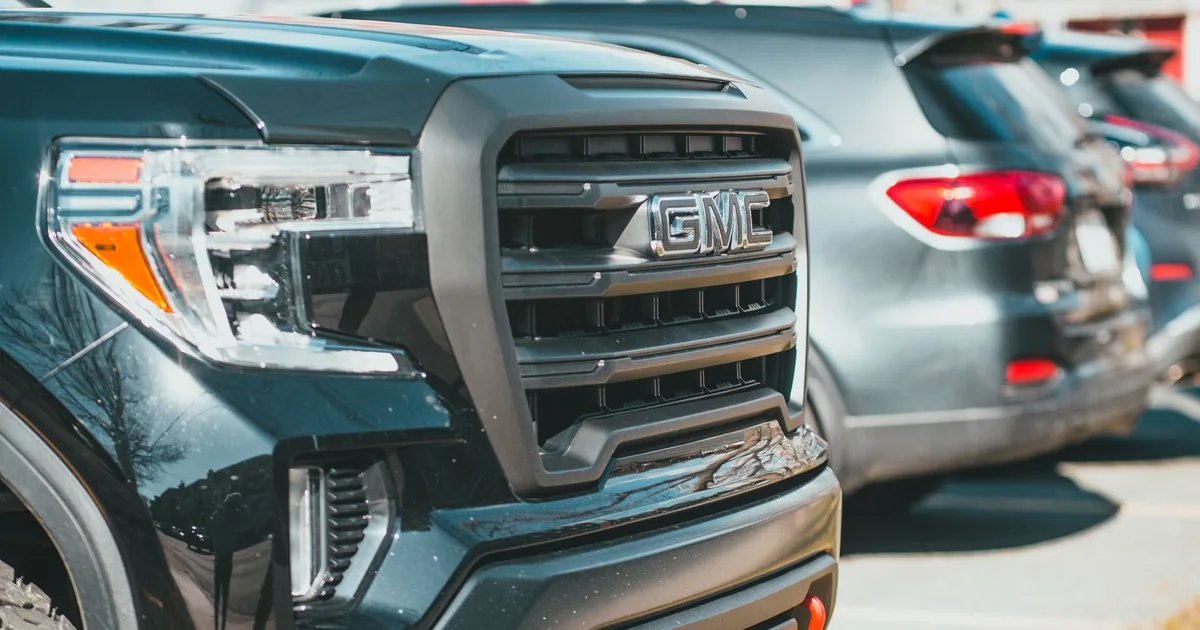 Close up of a black vehicle in a parking lot with other cars in the.
