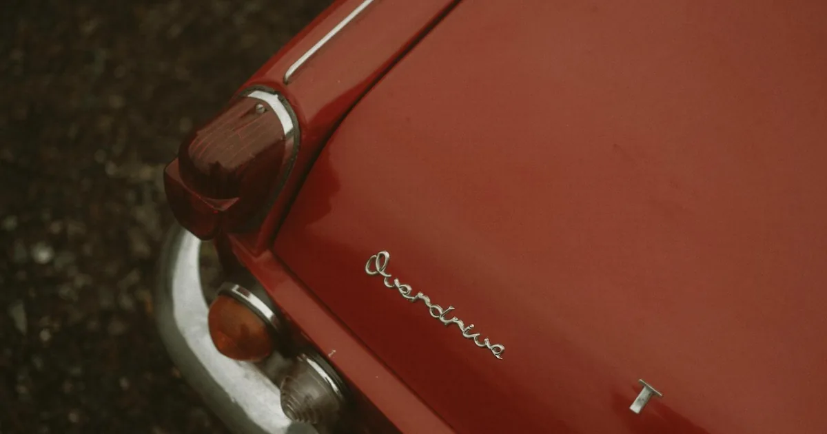 Close up of a red car s rear with a vintage design in a parking area.