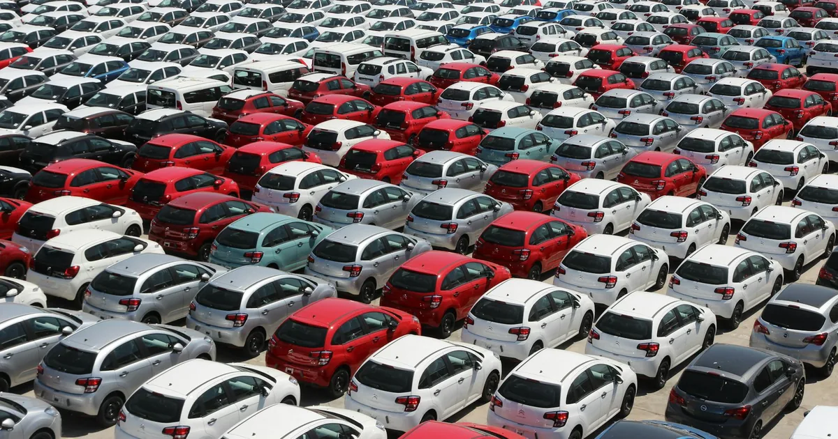 Crowded parking lot filled with rows of red and white vehicles.