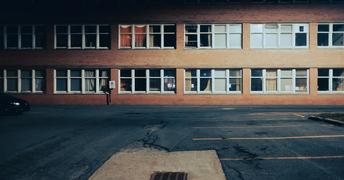 Dimly lit parking lot in front of a brick building with multiple.